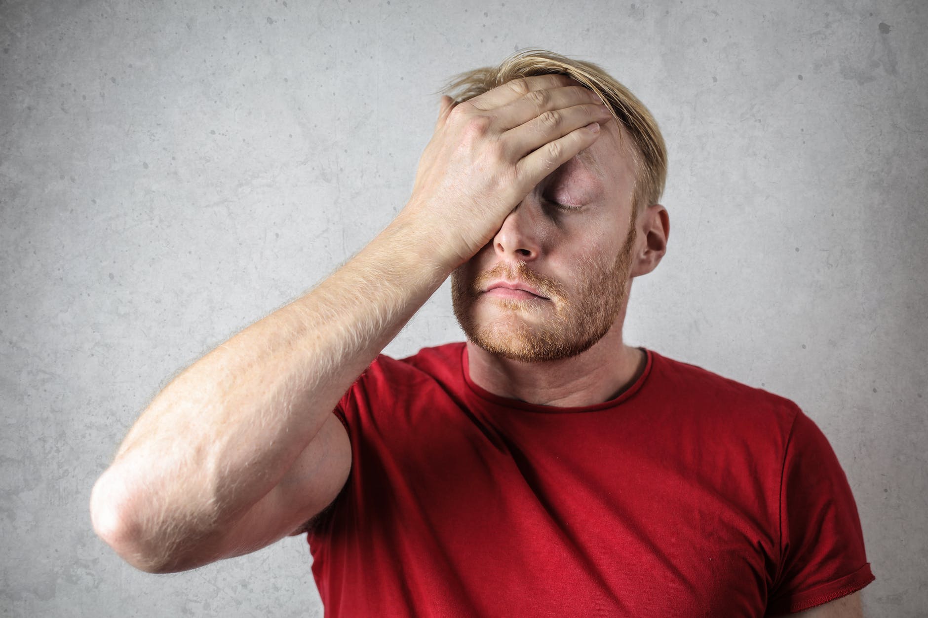 a man in red shirt covering his face